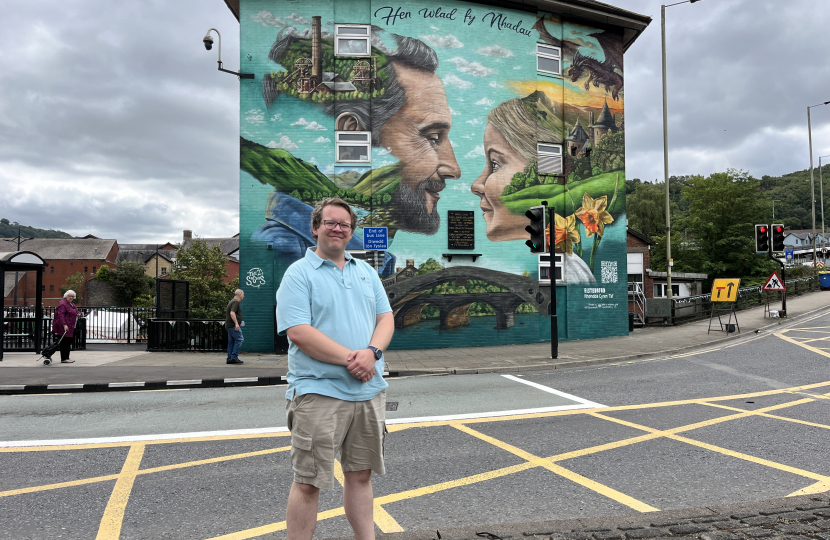 Joel James MS standing by Tee2Sugars Pontypridd mural