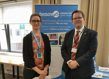 Joel James with a representative from Tenovus Cancer Care in the Senedd